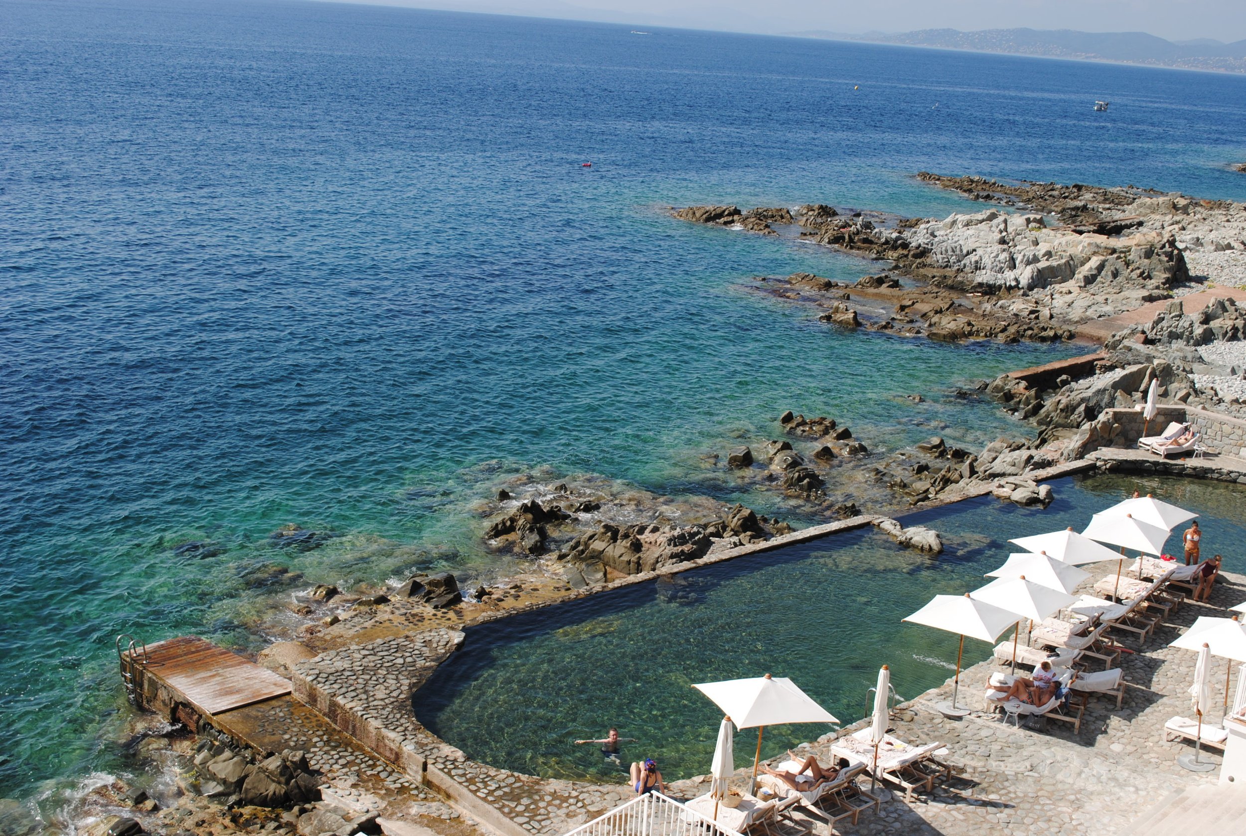 A coastal scene with clear blue water and rocky shore.
