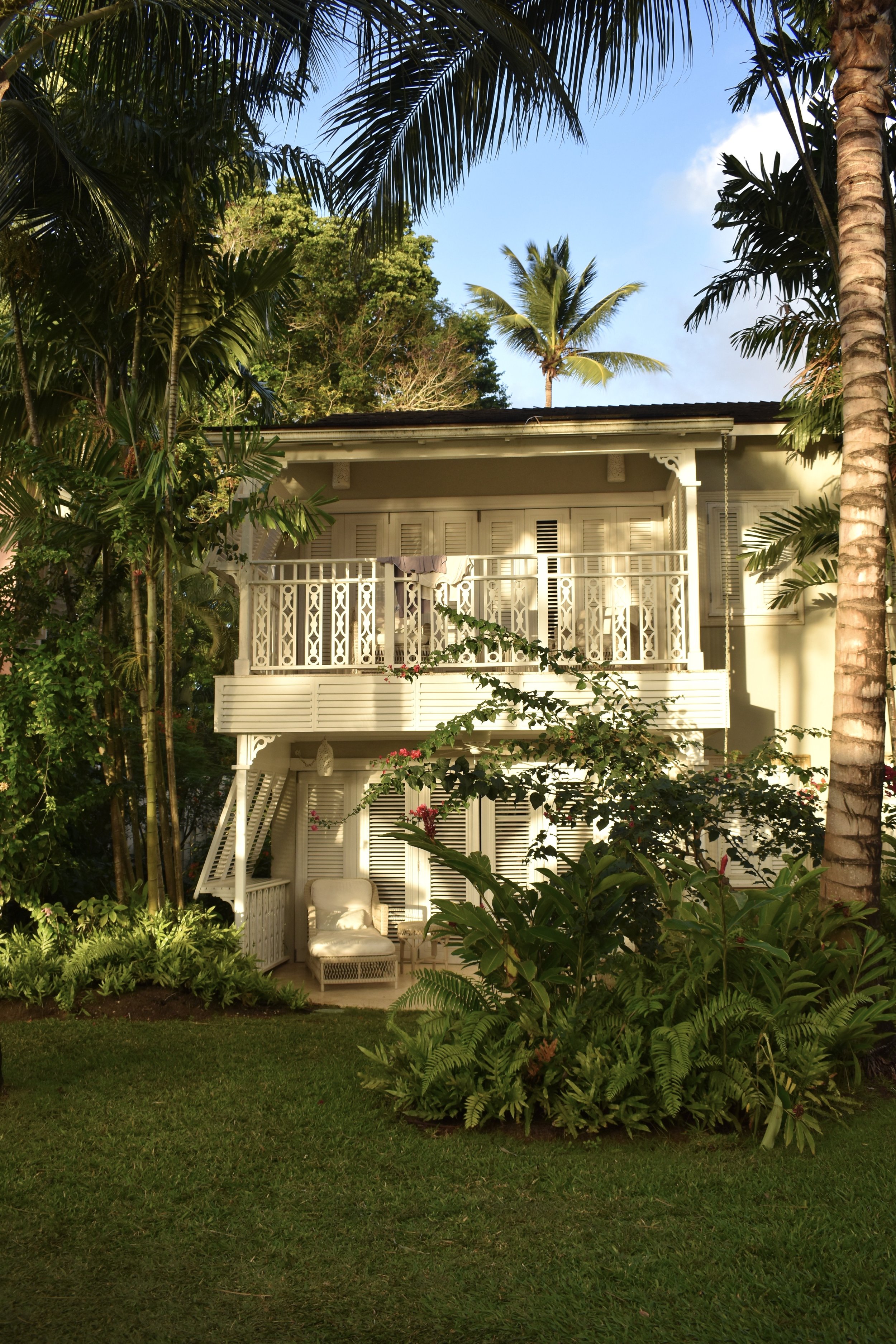 A standalone cottage at Cobbler's Cove framed by tropical greenery.