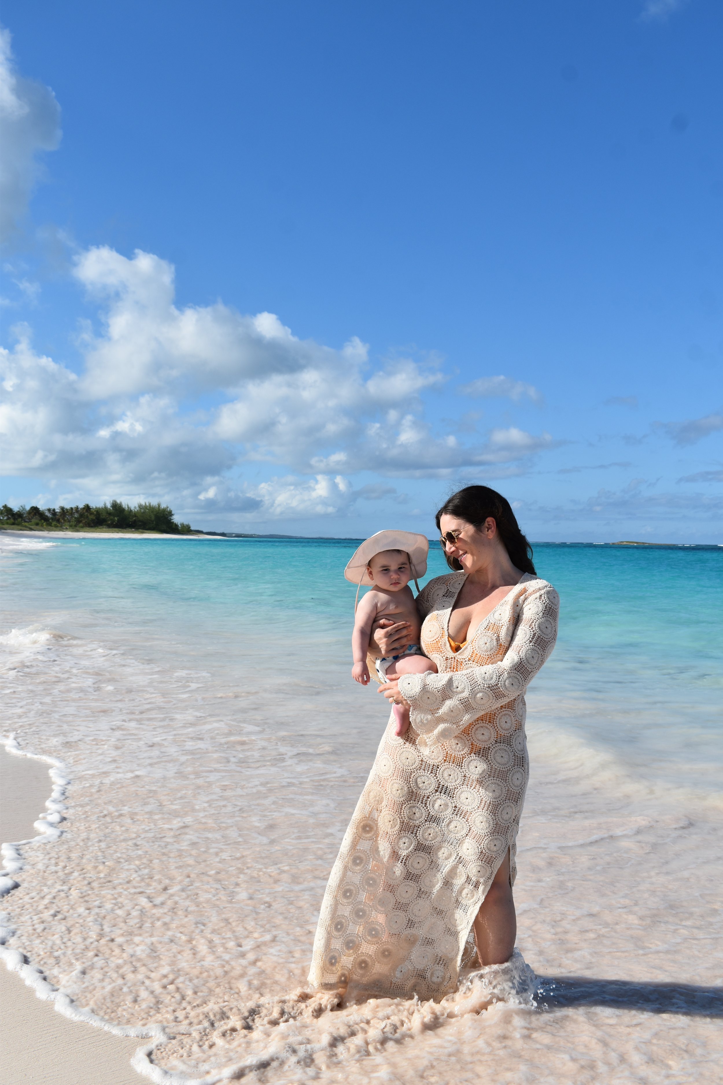 Julia holding a young child at the beach.
