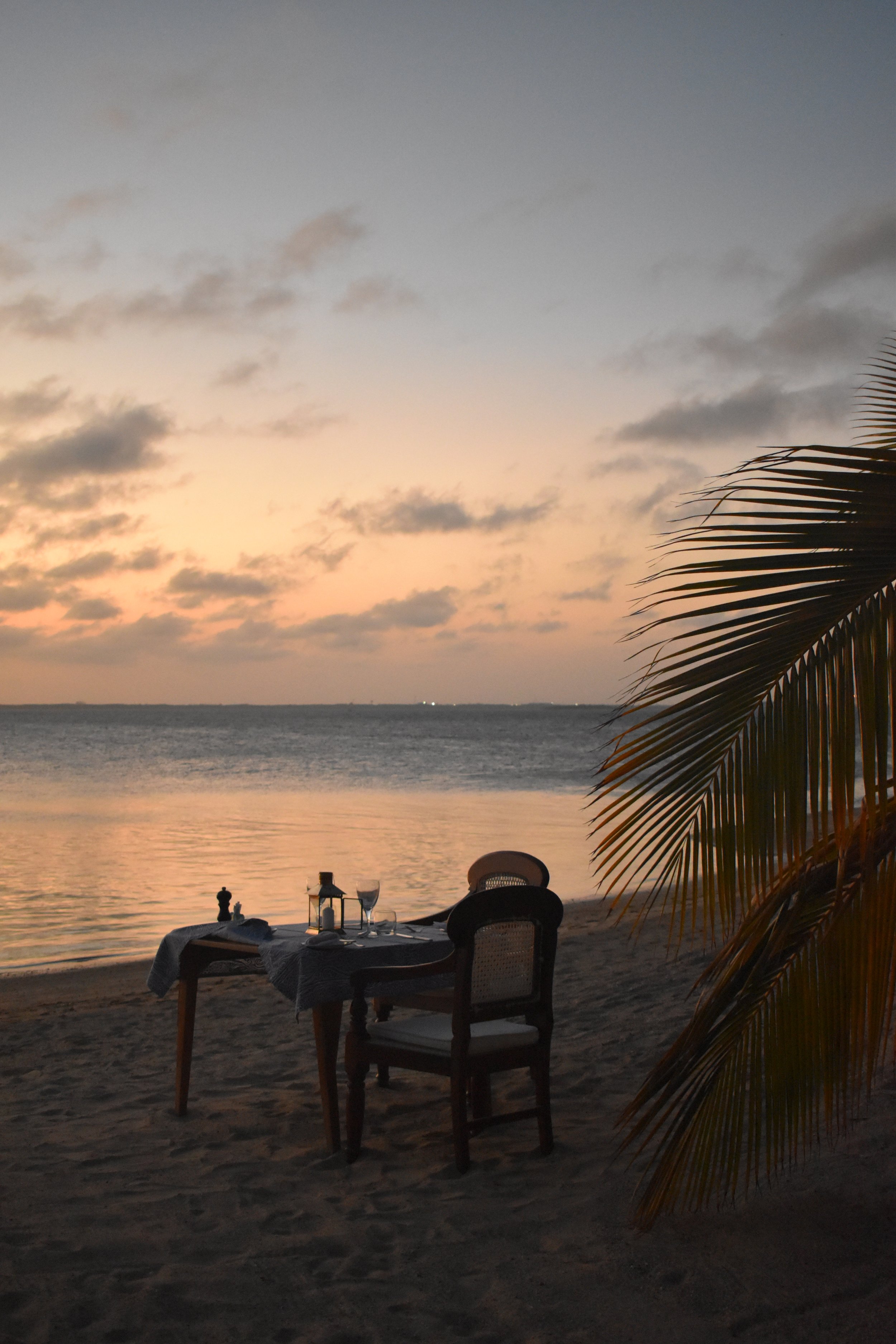 A beach at sunset with a table set for dinner.