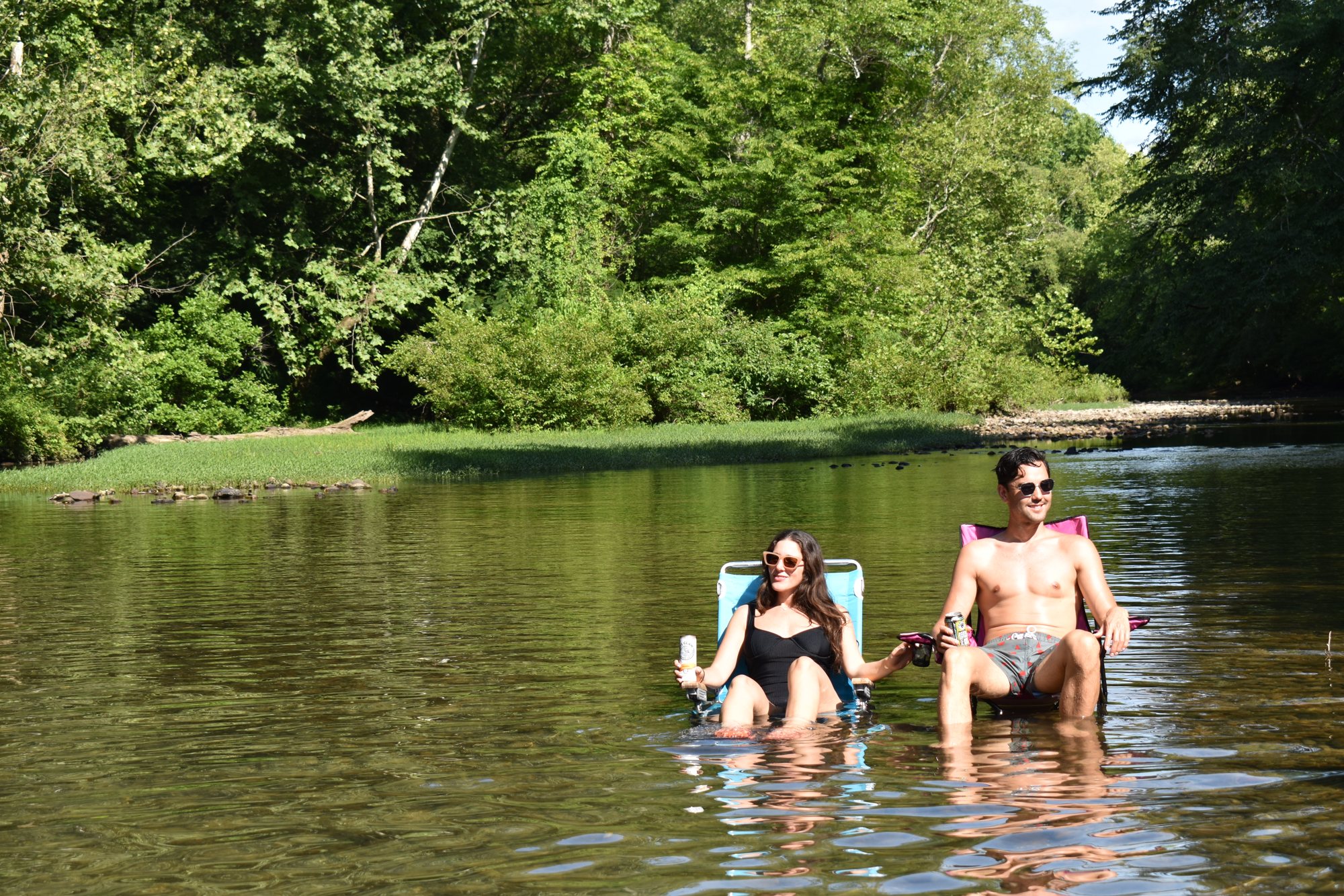 Floating in a creek under the trees, drinks in hand.
