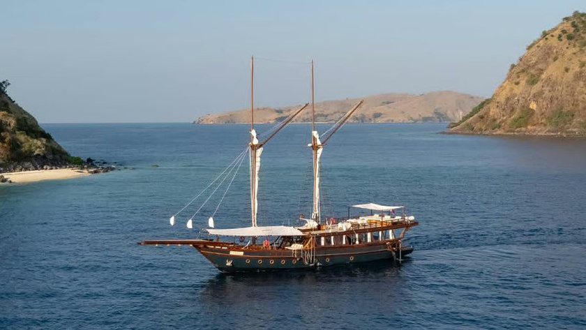 A twin-masted sailing boat anchored between islands.