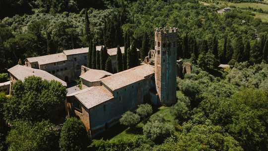 A historic abbey tower rising from Umbrian woodland.