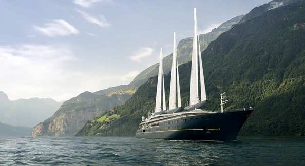 The Orient Express Olympian sailing yacht along a mountainous coast.