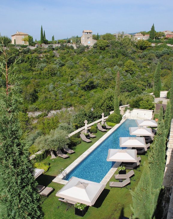 A long pool lined with umbrellas in the Provence hills.