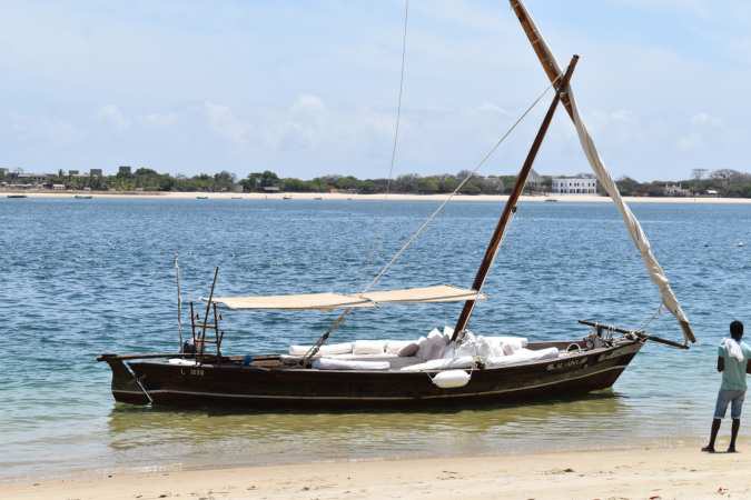 A traditional sailing boat anchored off a beach.