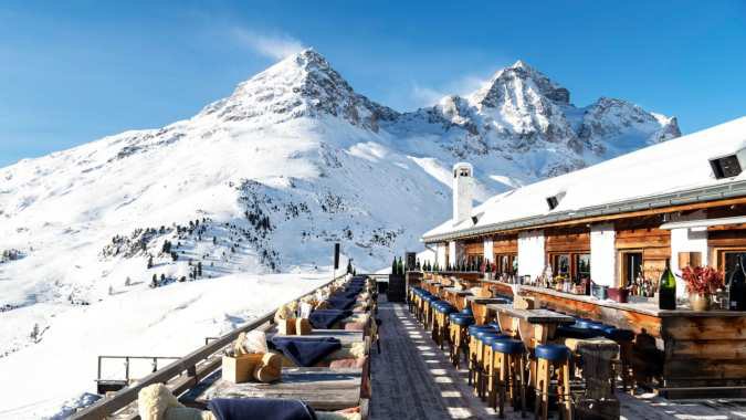 A mountain restaurant terrace surrounded by snowy peaks.