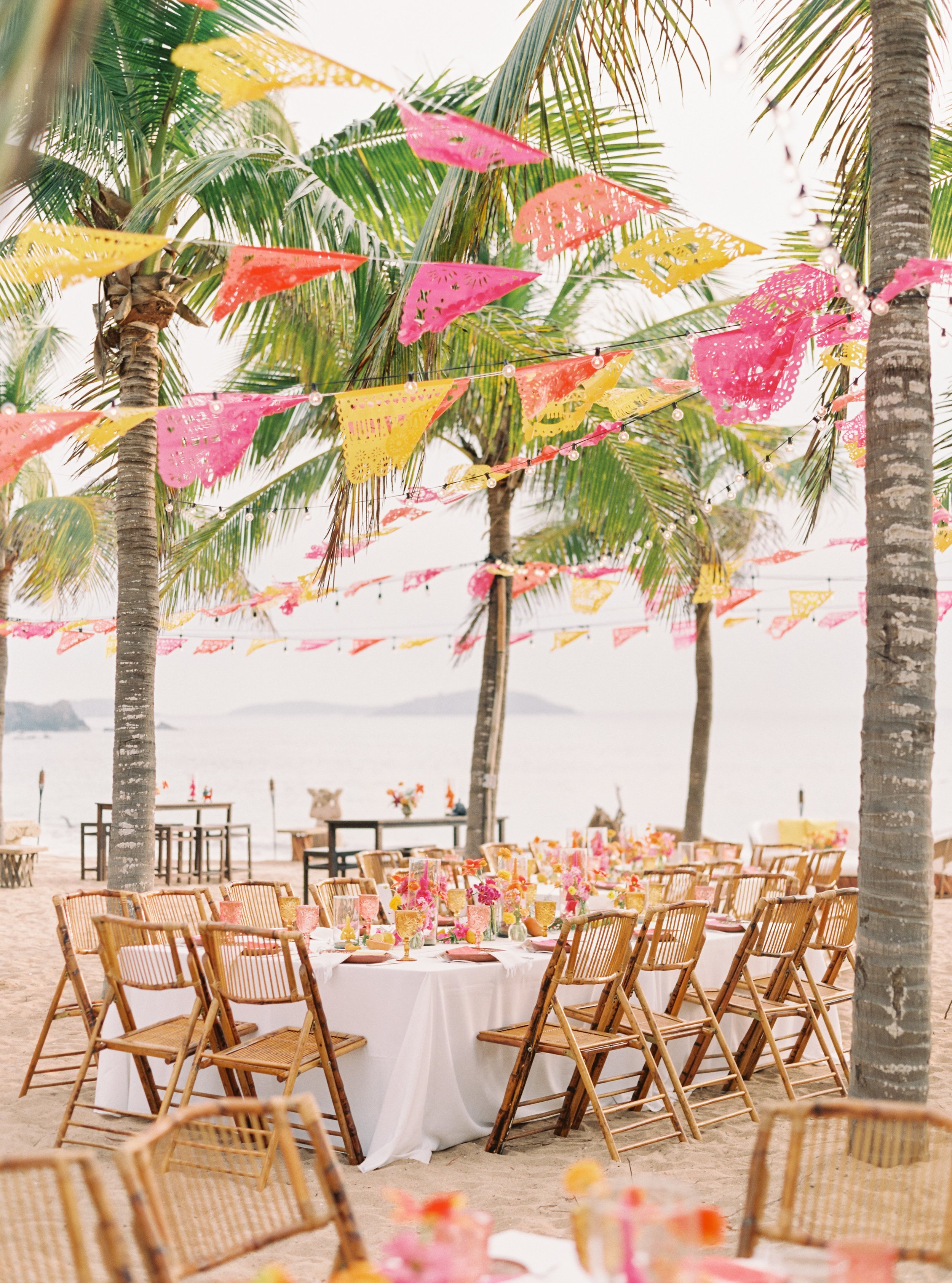 Destination wedding dinner on a beach in warm evening light.