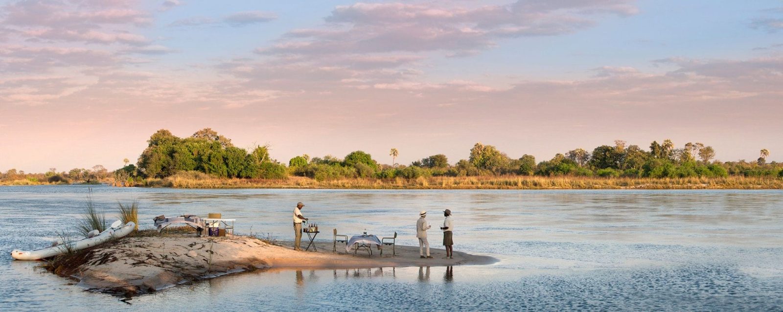 Boats pulled up to a sandbar picnic on the Zambezi.